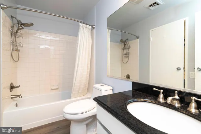 a bathroom with a granite countertop sink toilet a shower and a mirror