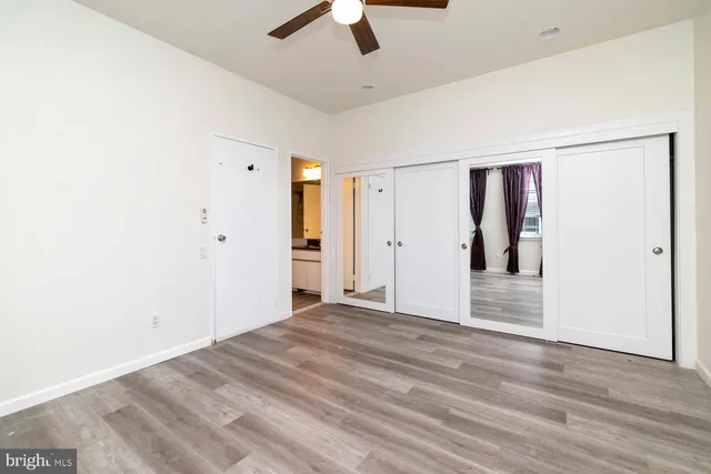a view of a livingroom with wooden floor a ceiling fan and a window