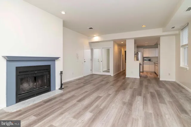 a view of an empty room with wooden floor fireplace and a window