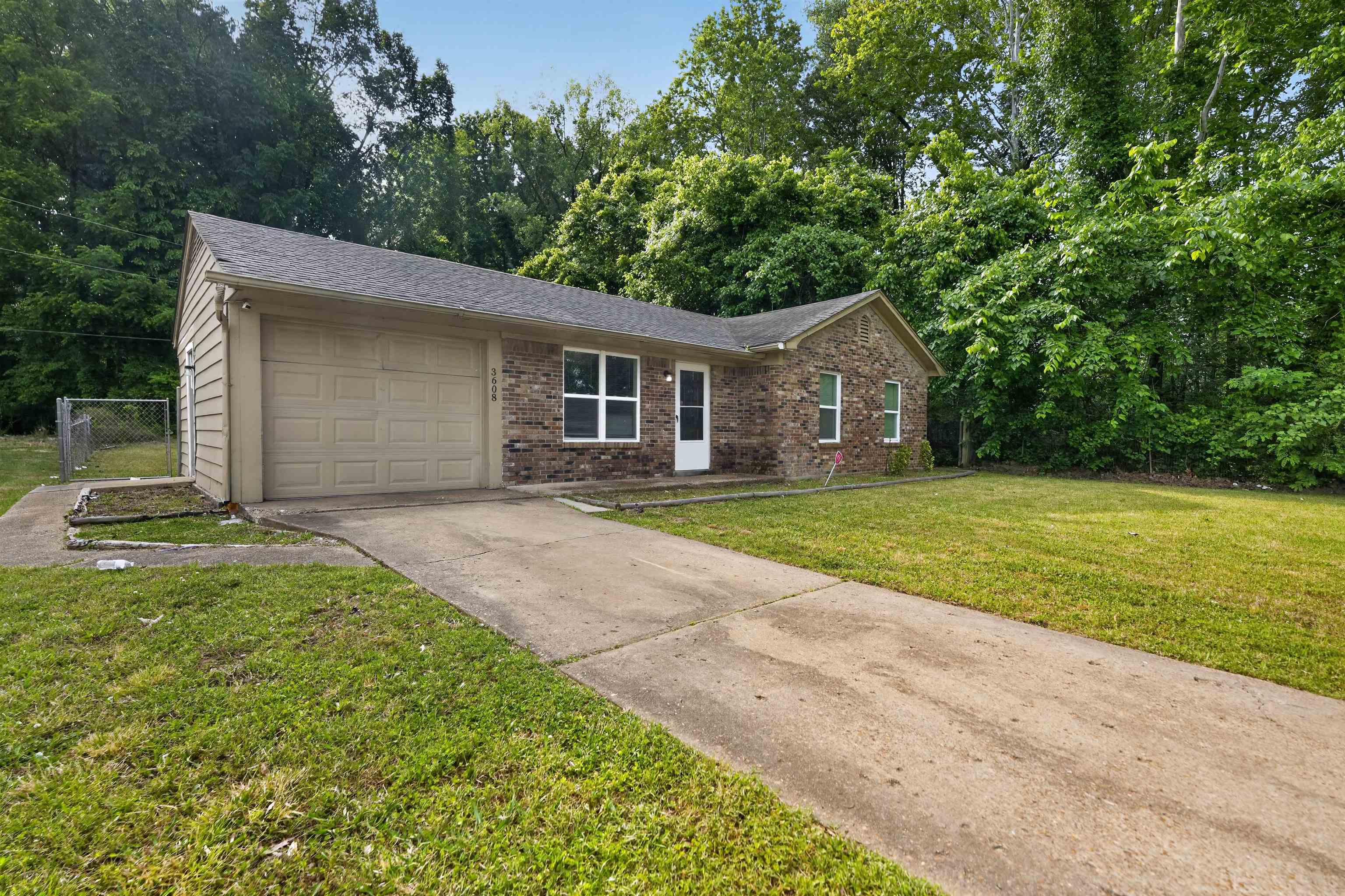 3608 Cane Ridge Drive Memphis, TN 38109 - Photo 11 of 31 Brick facade home featuring an attached garage, a concrete driveway, and a chain-link fence