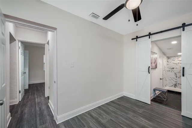 a view of a hallway with wooden floor and a ceiling fan