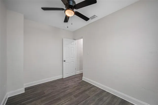 an empty room with wooden floor and ceiling fan