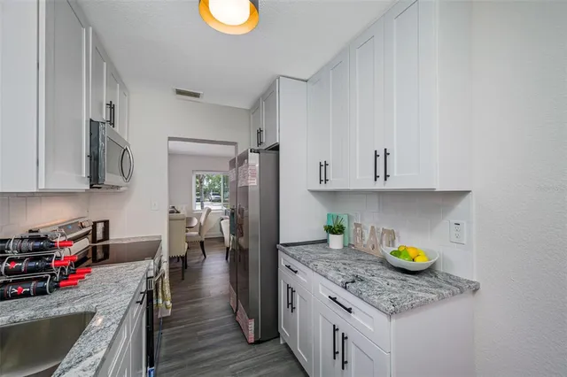a kitchen with stainless steel appliances granite countertop a lot of counter space and wooden floors