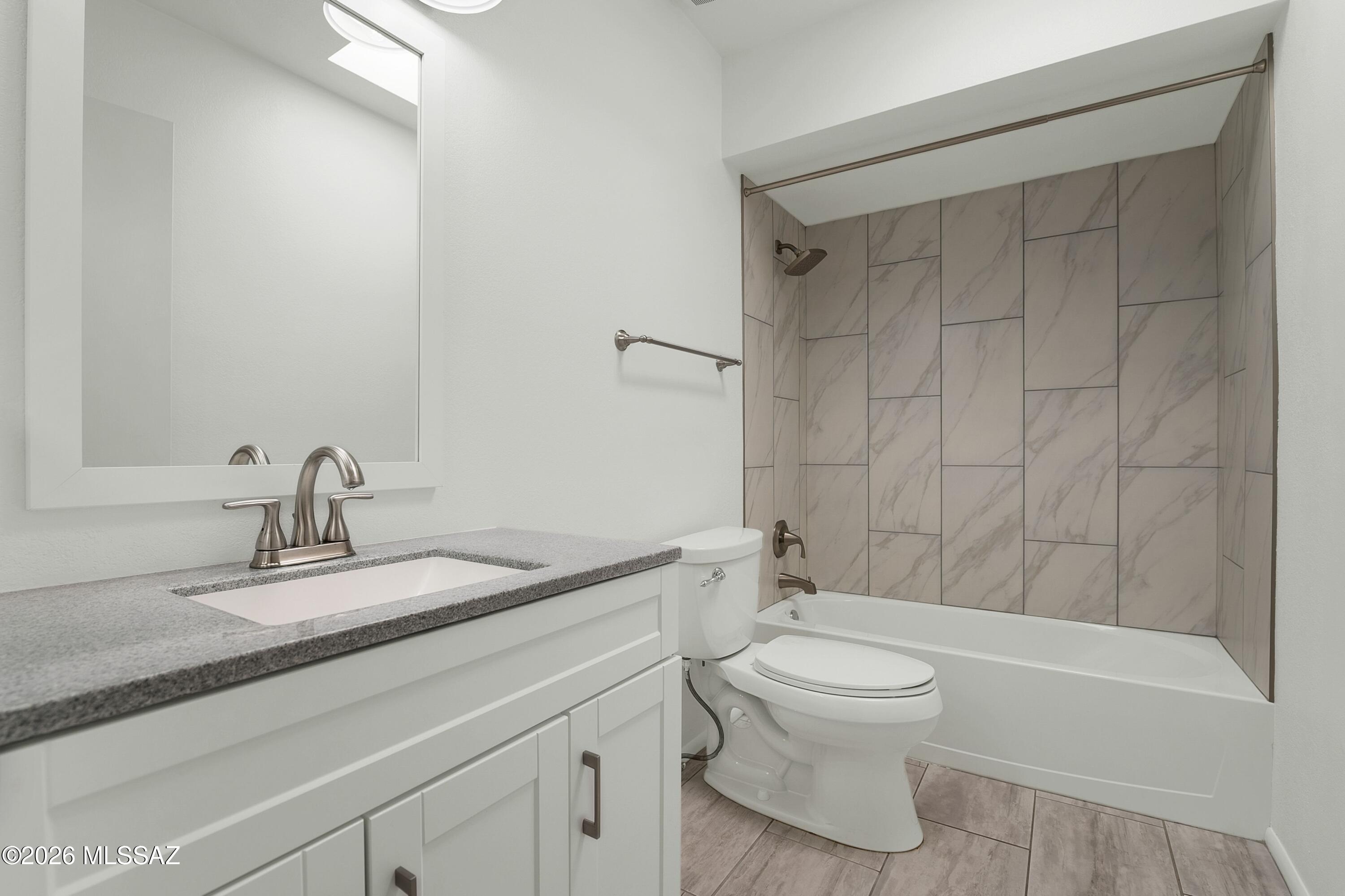 7408 East Wandering Road Tucson, AZ 85750 - Photo 20 of 25 a bathroom with a granite countertop sink a toilet and a bathtub