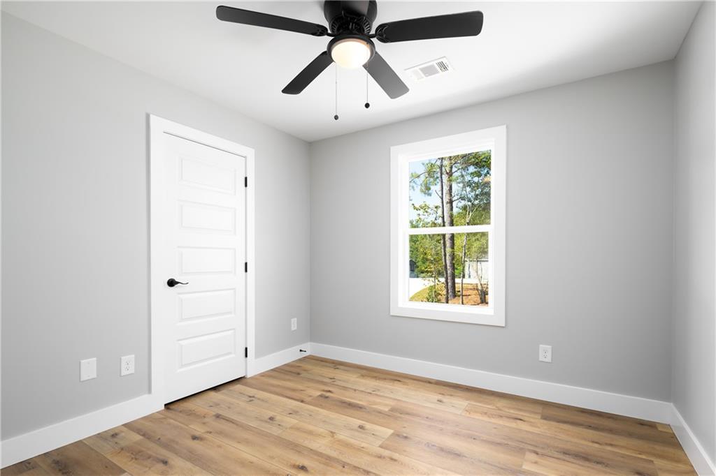 111 Lee Road Phenix City, AL 36867 - Photo 19 of 23 Wood-finish flooring, white trim, ceiling fan with integrated lighting, and a white paneled door with black hardware