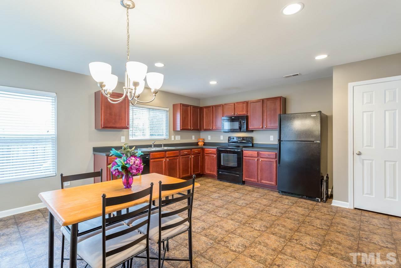3404 Kernstown Drive Raleigh, NC 27610 - Photo 5 of 21 a kitchen with stainless steel appliances granite countertop a refrigerator a sink dishwasher a dining table and chairs with wooden floor