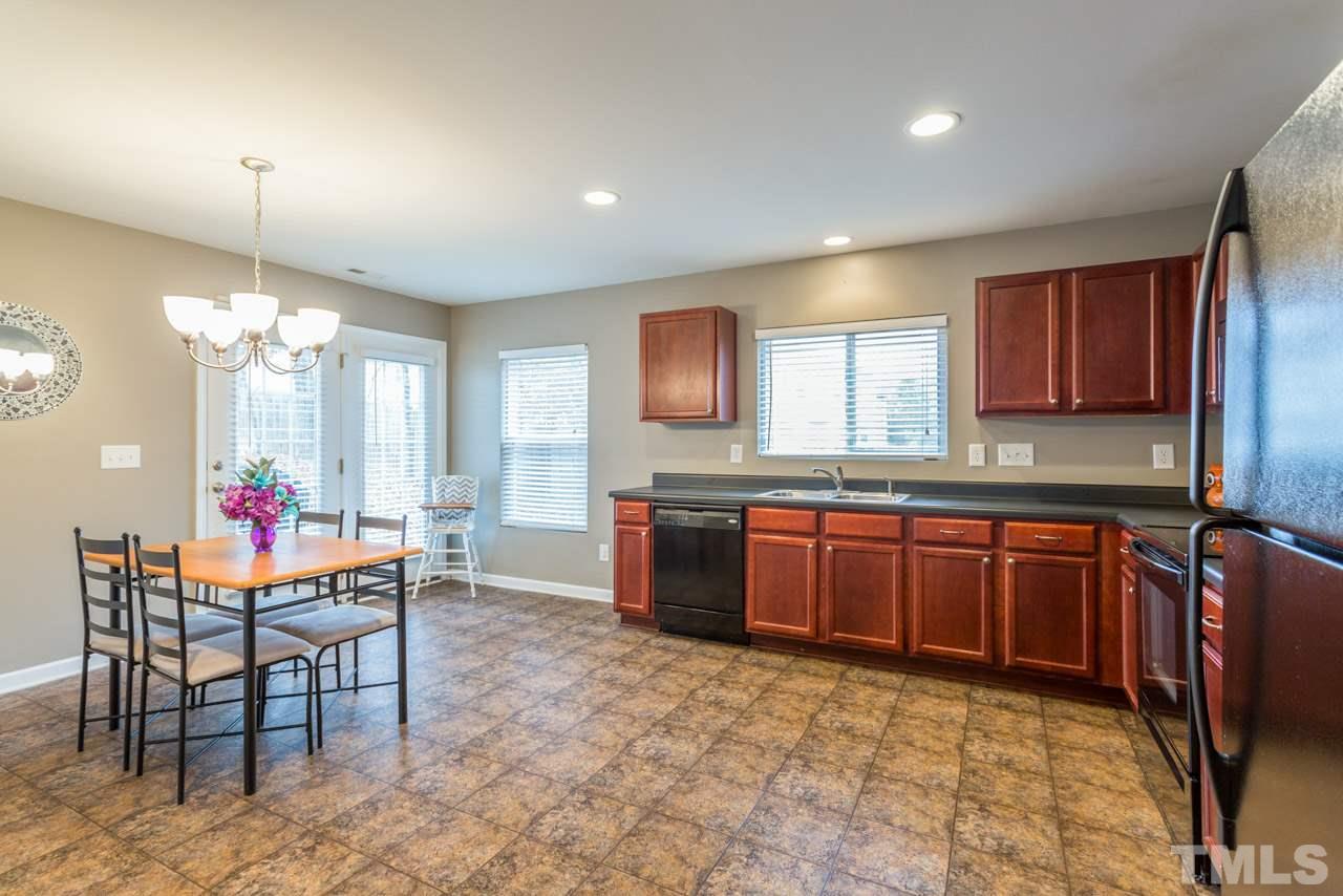 3404 Kernstown Drive Raleigh, NC 27610 - Photo 6 of 21 a large kitchen with granite countertop a stove a sink dishwasher a dining table and chairs with wooden floor