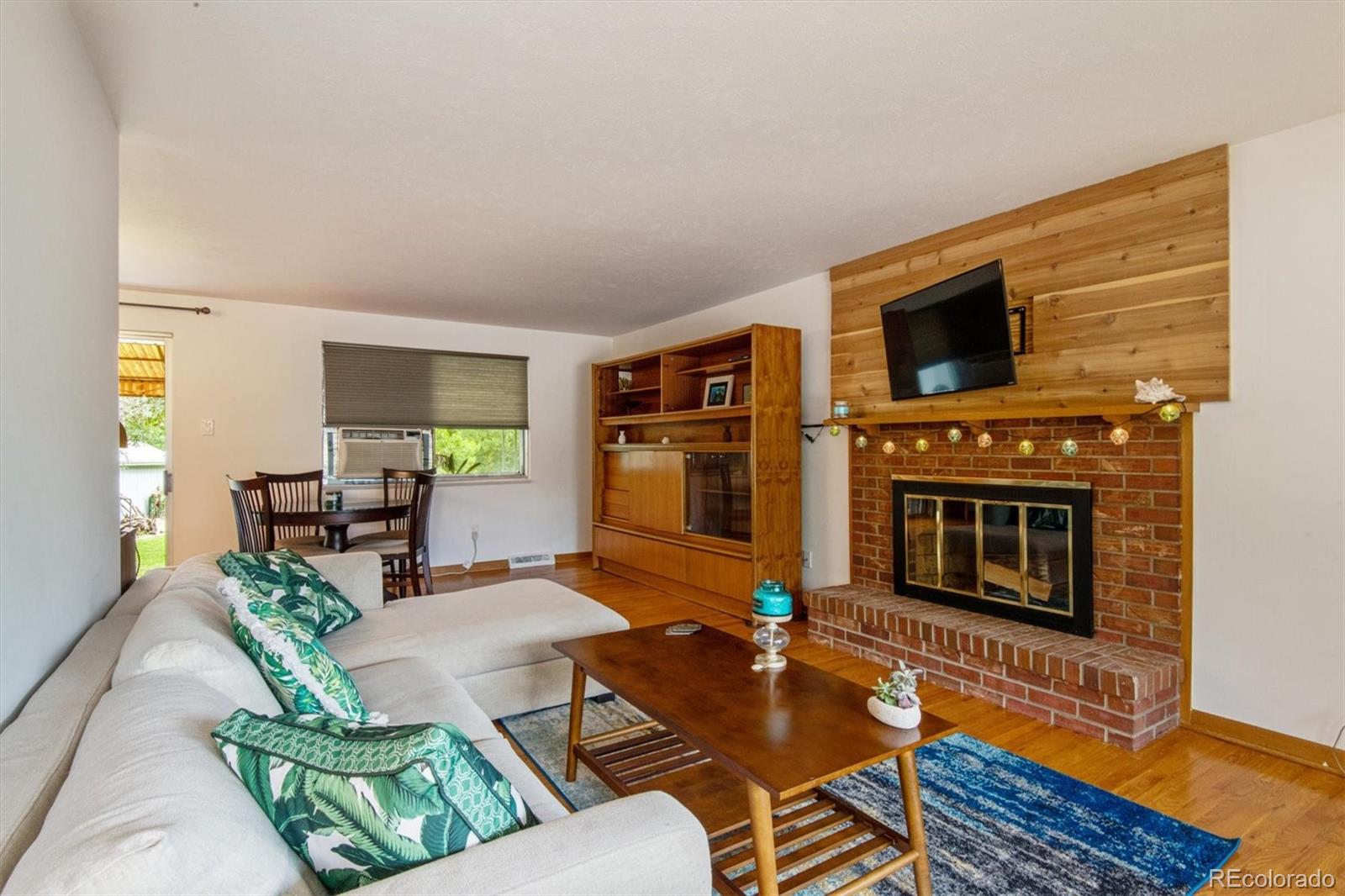 8633 West 44th Place Wheat Ridge, CO 80033 - Photo 4 of 30 a living room with furniture a flat screen tv and a fireplace