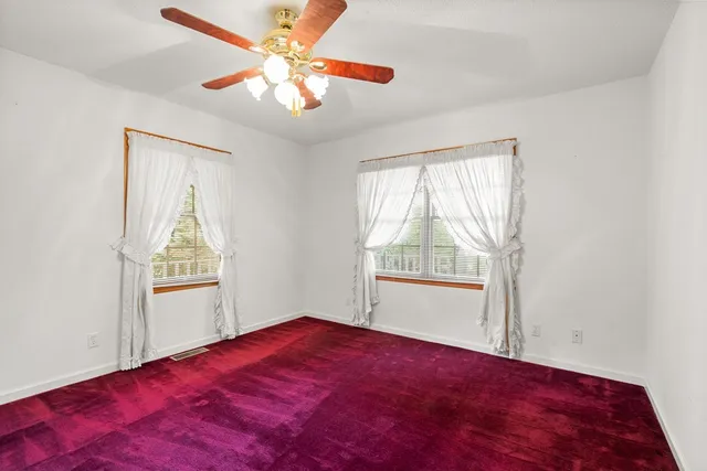 a view of a bedroom with windows and ceiling fan