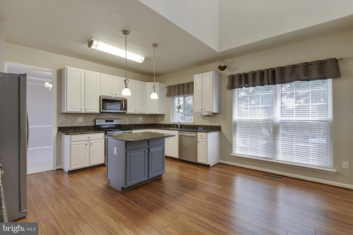 12902 Summit Ridge Terrace Germantown, MD 20874 - Photo 11 of 30 a kitchen with granite countertop wooden floors stainless steel appliances and sink