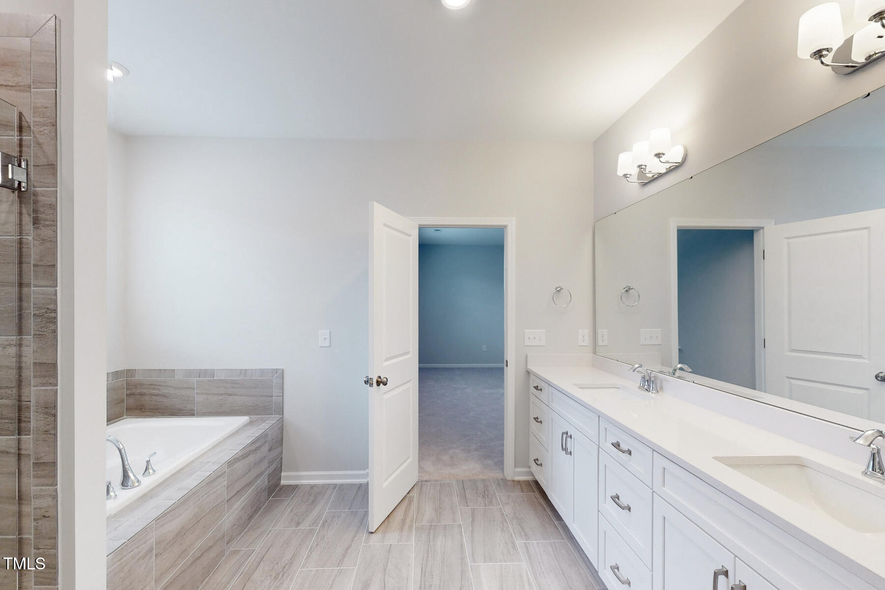 7701 Litcham Drive Raleigh, NC 27615 - Photo 35 of 58 a spacious bathroom with a double vanity sink a mirror and a bathtub