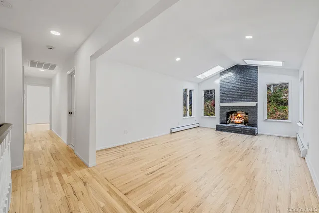 a view of empty room with wooden floor and fireplace