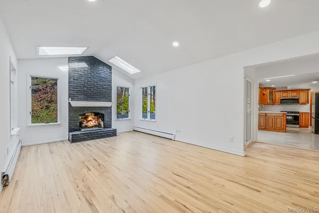 a view of an empty room with wooden floor fireplace and a window