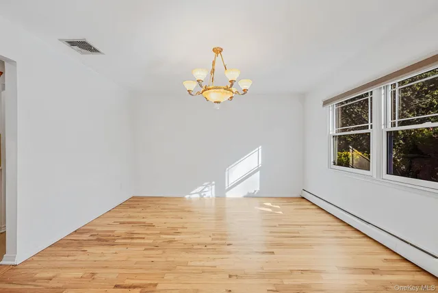 a view of empty room with wooden floor and window