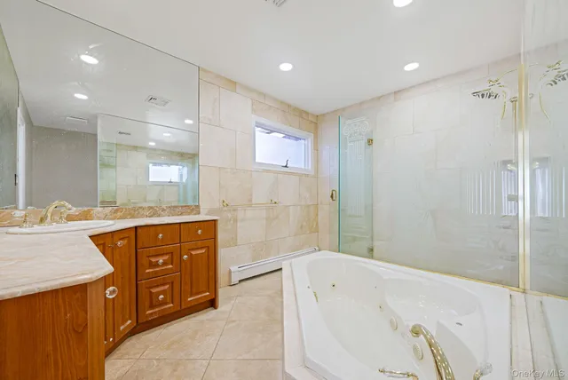a bathroom with a bathtub shower sink and mirror