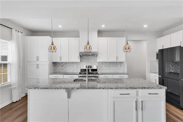a kitchen with stainless steel appliances granite countertop a sink a stove a refrigerator a center island and cabinets