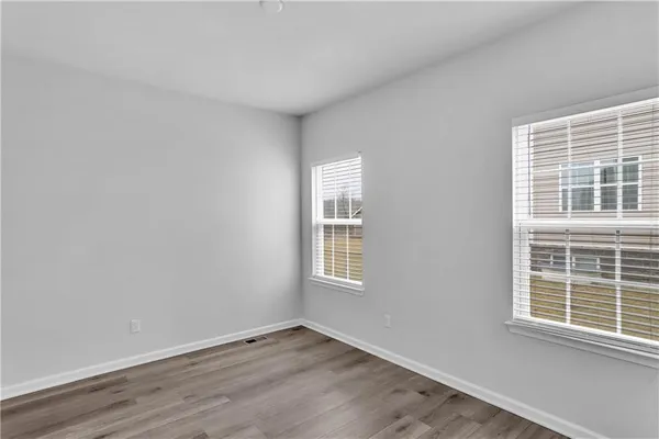 a view of an empty room with wooden floor and windows