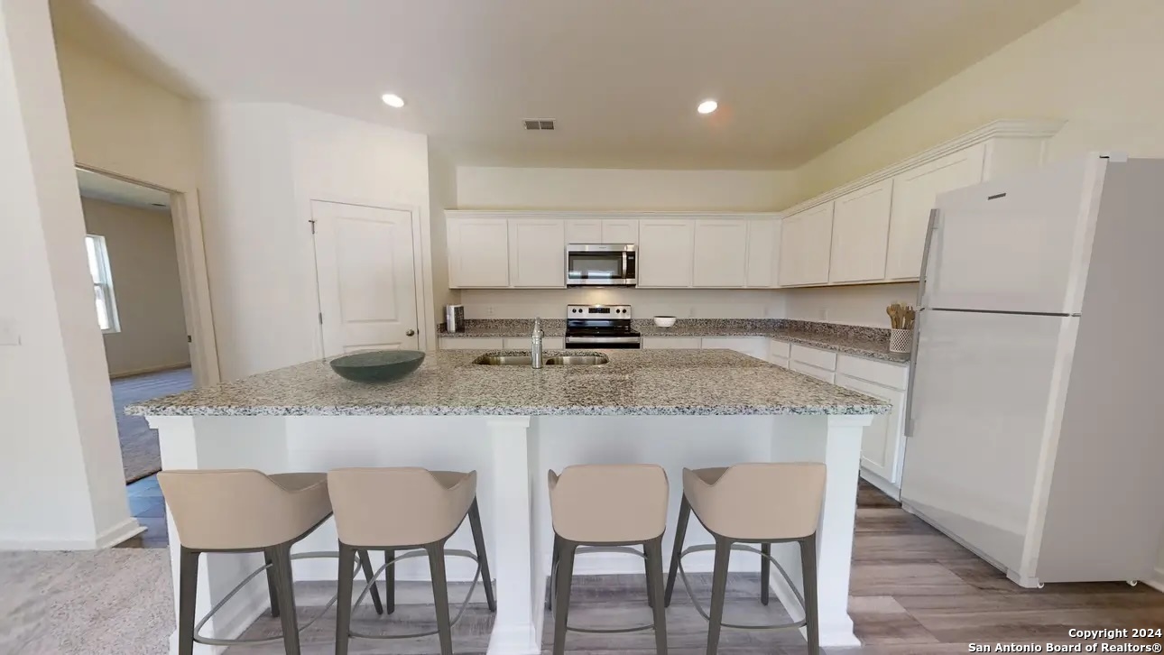 10502 Lesser Snow Adkins, TX 78101 - Photo 2 of 12 a kitchen with kitchen island granite countertop a table chairs refrigerator and microwave