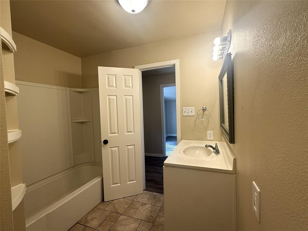 4718 Normandy Road Fort Worth, TX 76103 - Photo 19 of 26 Bathroom featuring a white vanity with integrated sink, a framed mirror, and a three-bulb vanity light fixture