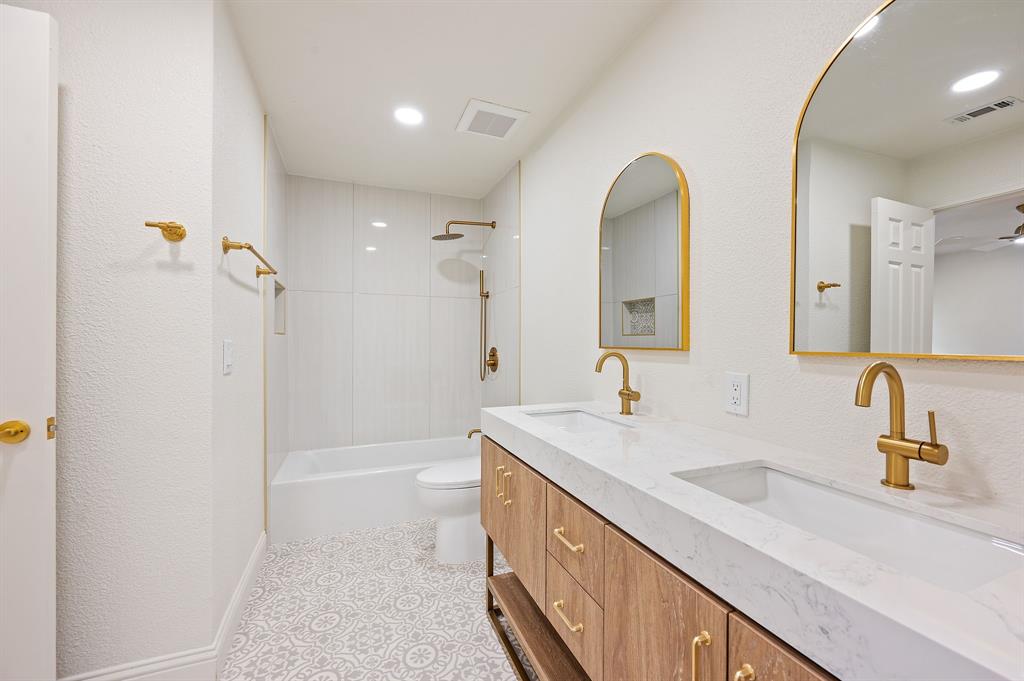 6403 Genstar Lane Dallas, TX 75252 - Photo 28 of 34 Bathroom featuring a dual vanity with integrated sinks, gold-tone fixtures, and arched mirrors