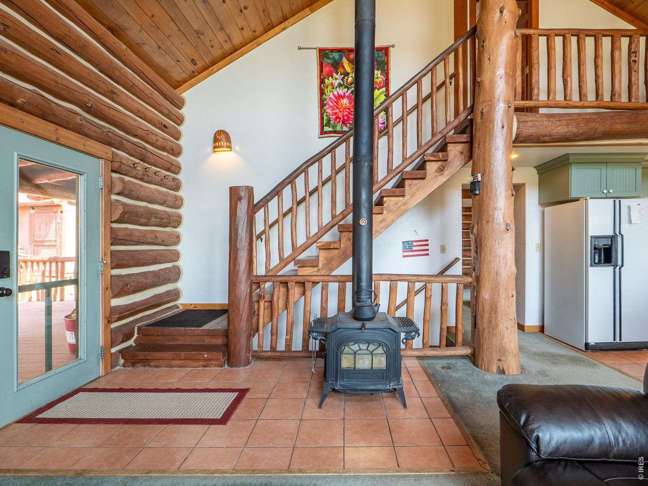 296 Caddo Road Red Feather Lakes, CO 80545 - Photo 6 of 50 Wood burning stove and open stairs to upper & lower floors.