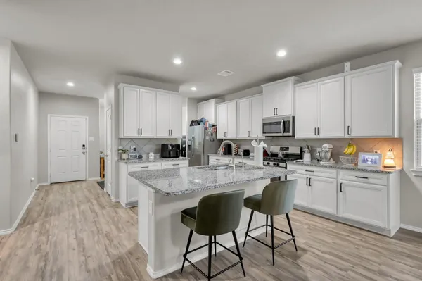 a kitchen with white cabinets stove and refrigerator