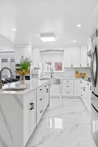 a kitchen with granite countertop a sink white cabinets and stainless steel appliances