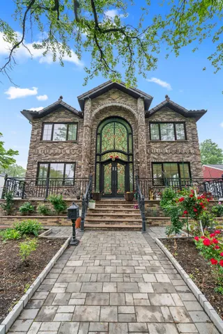 a view of a brick house with a small yard plants and large tree