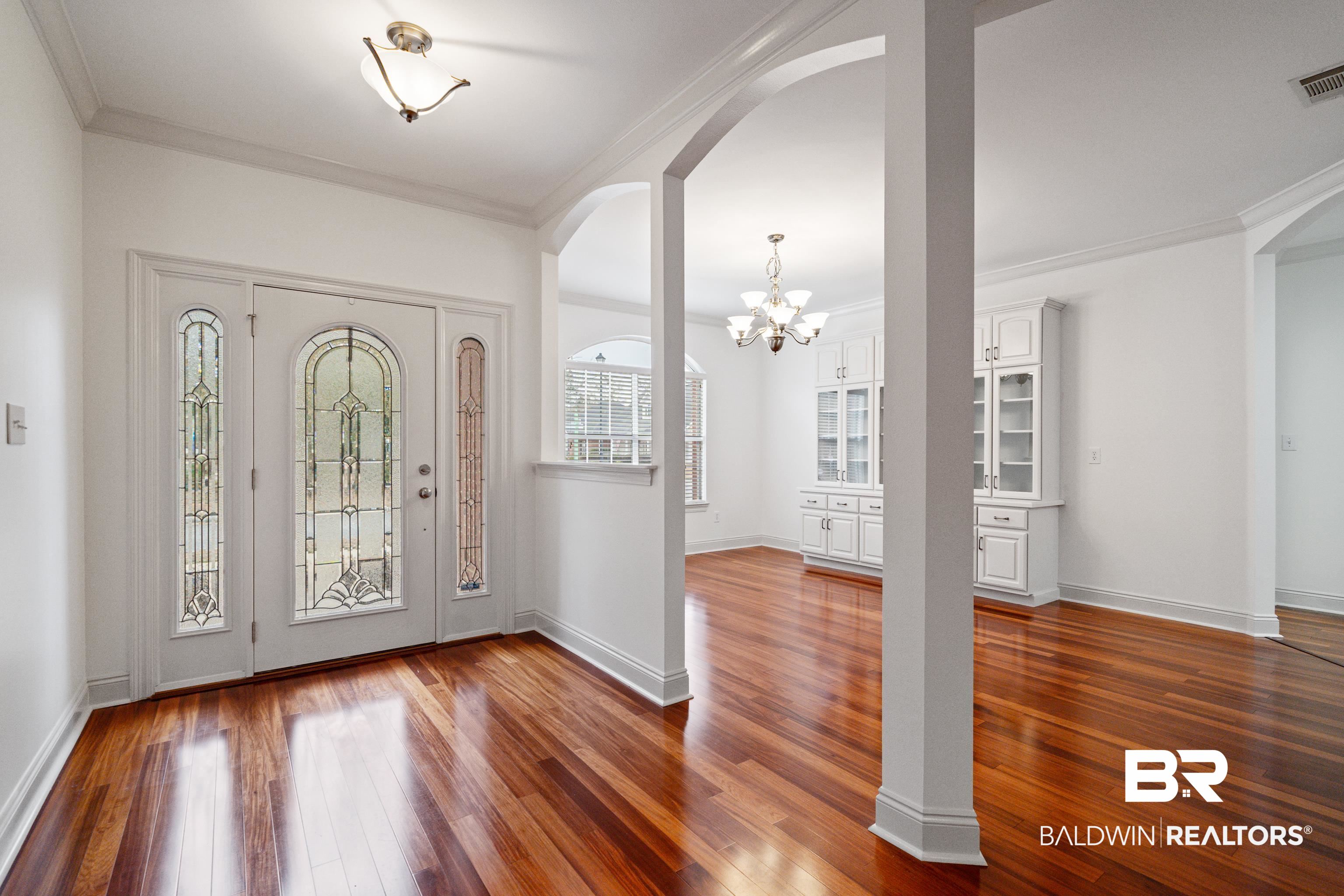 404 Savannah Lane Foley, AL 36535 - Photo 5 of 29 Entrance foyer with baseboards, arched walkways, dark wood-type flooring, crown molding, and a notable chandelier
