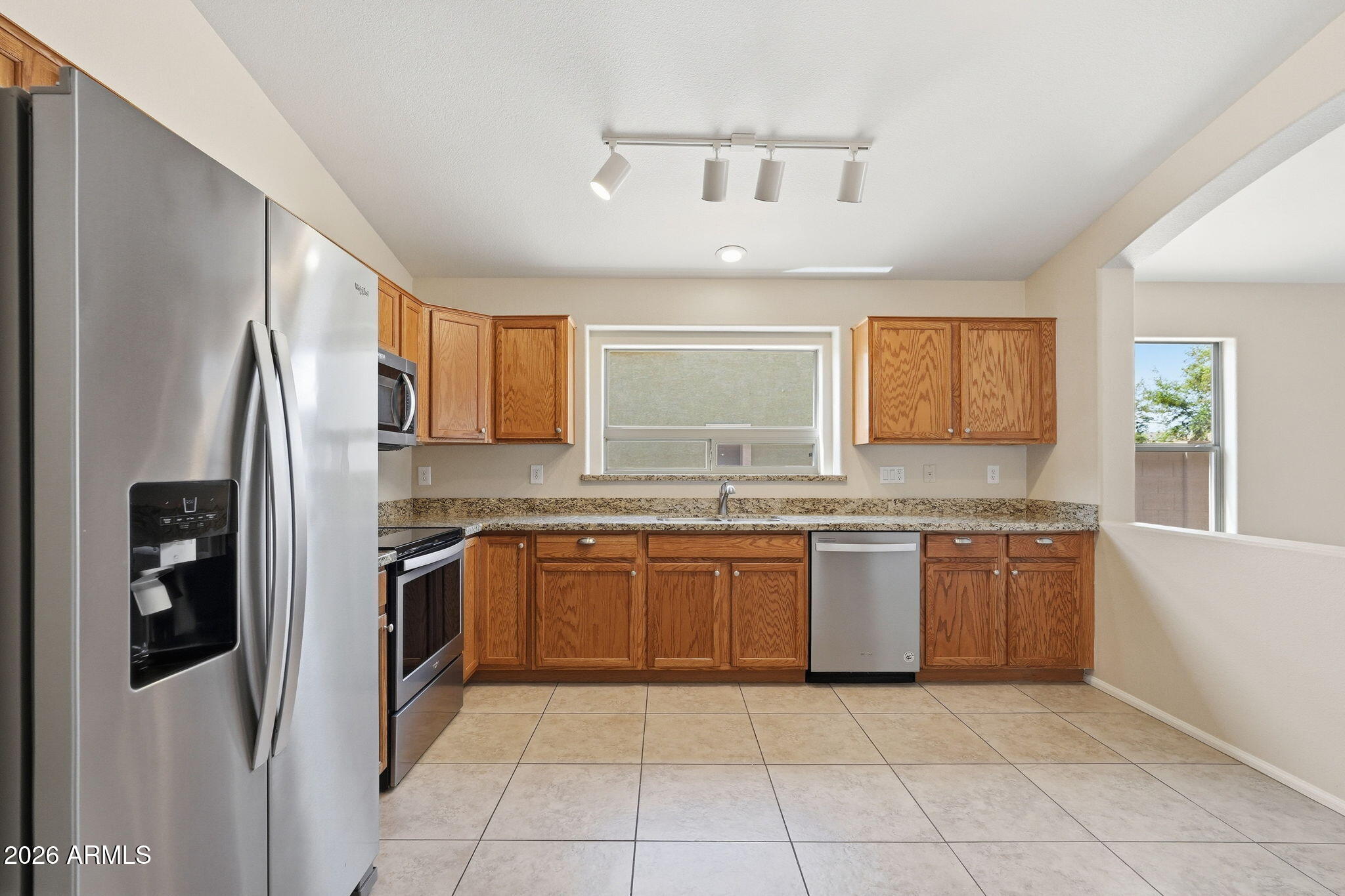 2022 South 160th Lane Goodyear, AZ 85338 - Photo 12 of 36 a large kitchen with granite countertop stainless steel appliances and a refrigerator