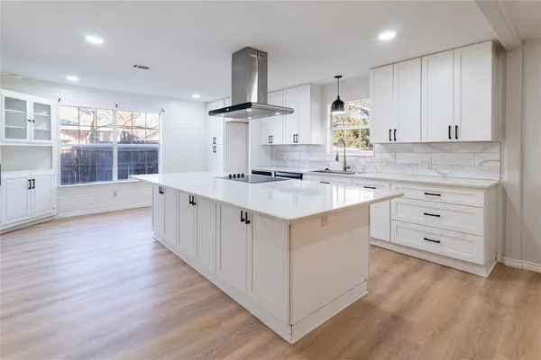 a kitchen with a sink stove cabinets and wooden floor