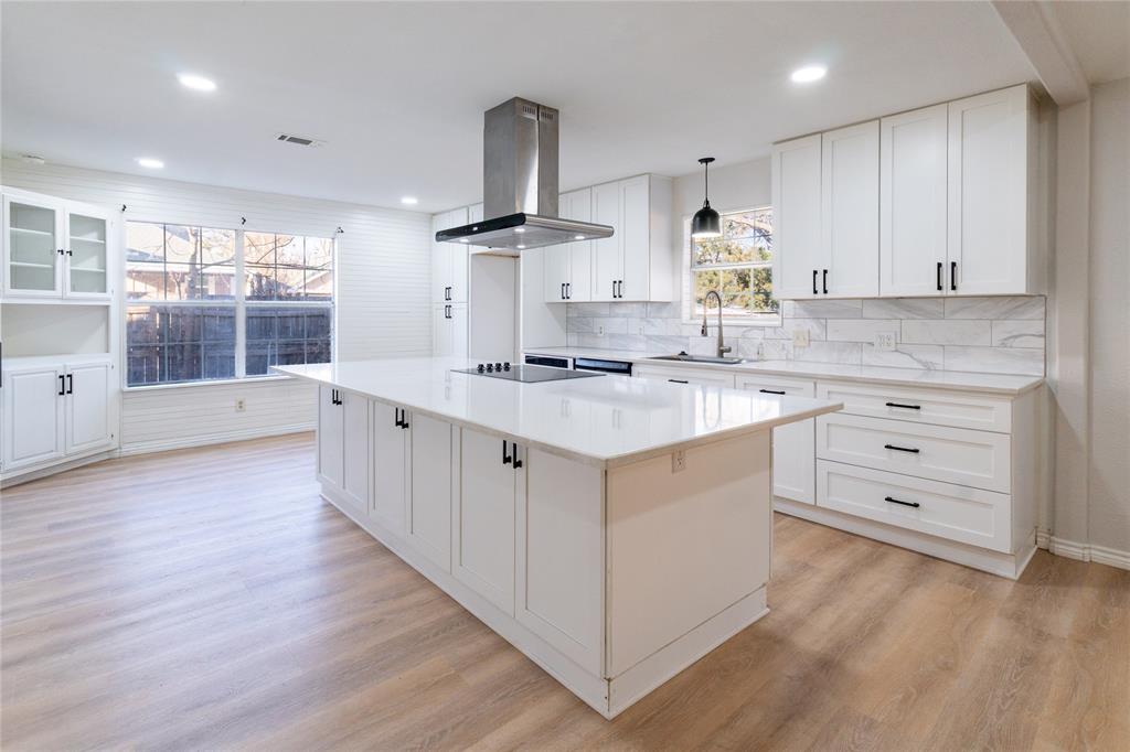 a kitchen with a sink stove cabinets and wooden floor