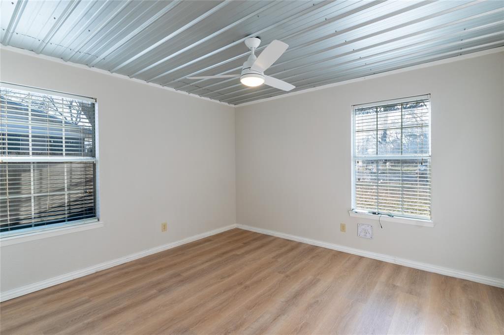313 South Prairie Street Pilot Point, TX 76258 - Photo 12 of 16 a view of an empty room with wooden floor and a window