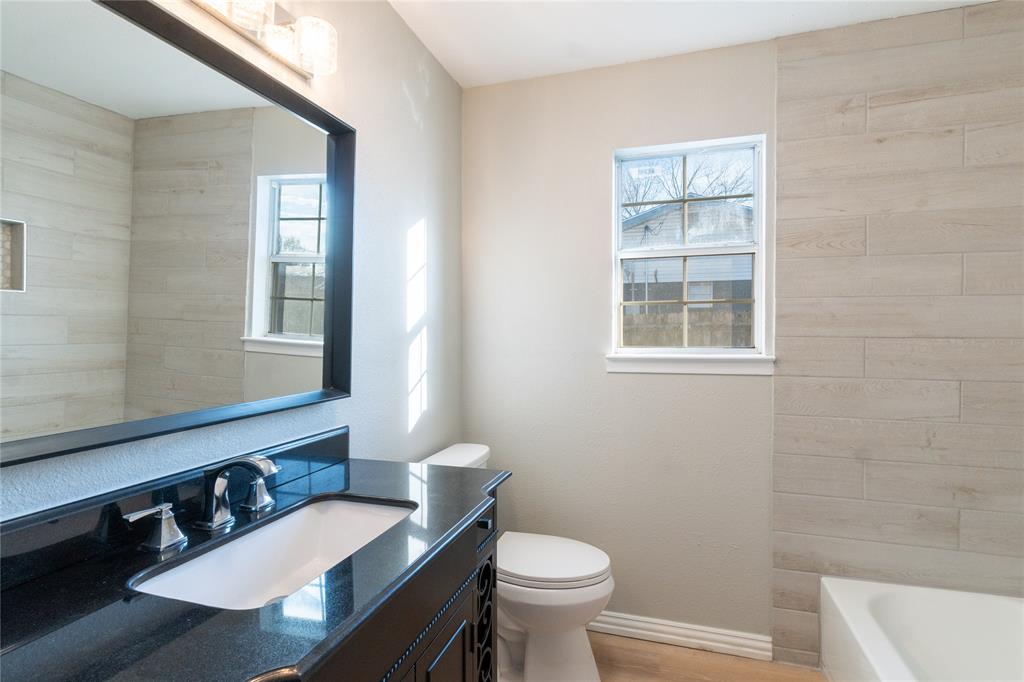 313 South Prairie Street Pilot Point, TX 76258 - Photo 13 of 16 a bathroom with a sink a toilet a mirror and shower