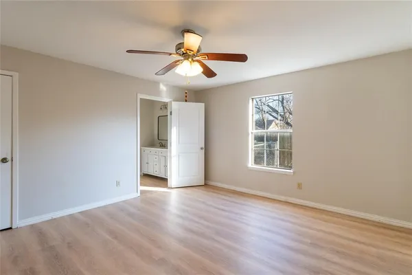 a view of an empty room with wooden floor and window