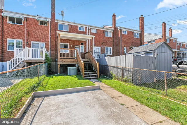 a view of a house with wooden fence next to a yard