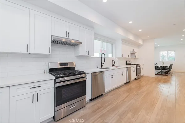 a kitchen with stainless steel appliances white cabinets and a wooden floor