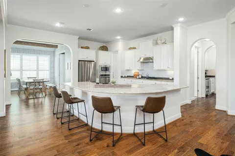 a large white kitchen with lots of counter space a sink and stainless steel appliances