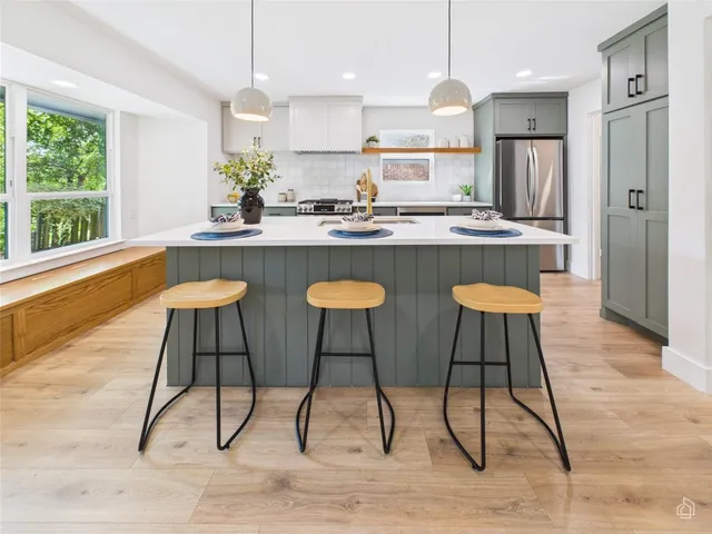a kitchen with stainless steel appliances granite countertop table chairs sink refrigerator and cabinets