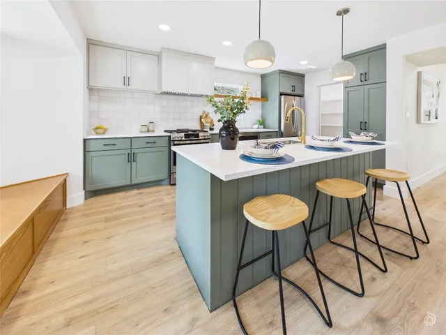 a kitchen with stainless steel appliances granite countertop a sink a stove a refrigerator and island with wooden floor