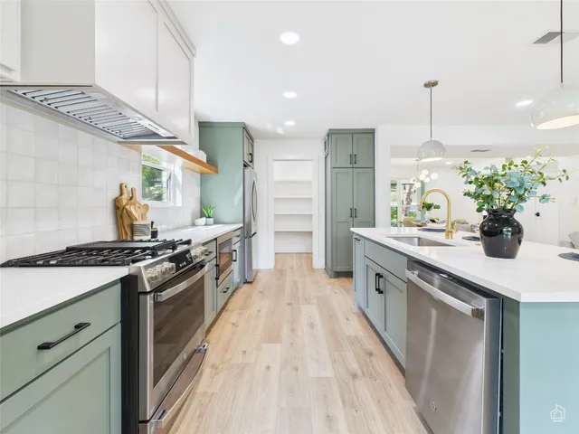 a large kitchen with stainless steel appliances granite countertop a stove a sink and a refrigerator