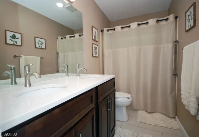 a bathroom with a sink a toilet a shower curtain and a mirror