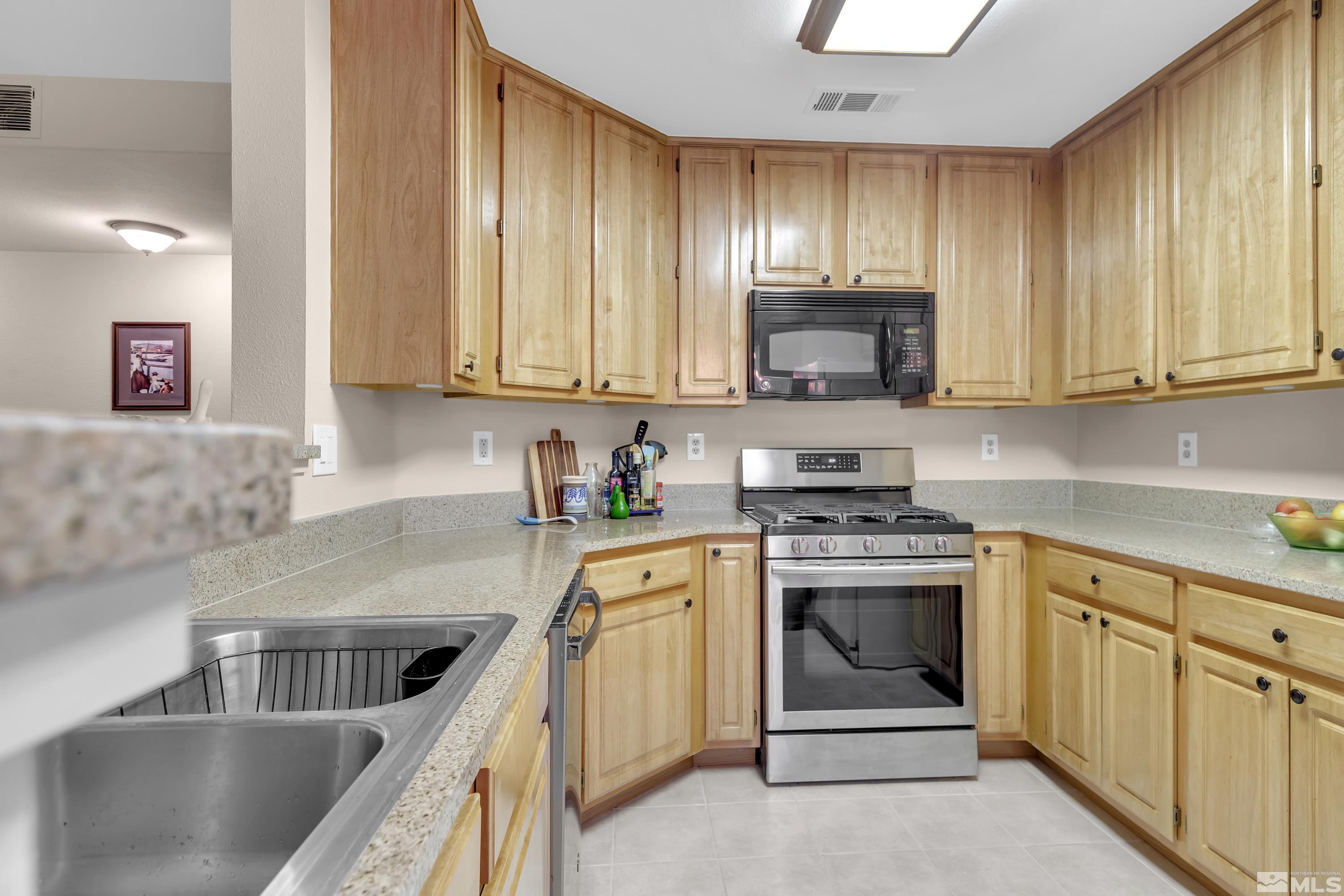 900 South Meadows Parkway, Unit 111 Reno, NV 89521 - Photo 10 of 35 a kitchen with wooden cabinets and a stove top oven