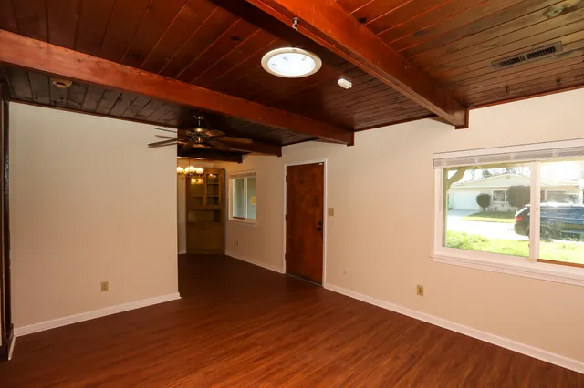 a view of an empty room with wooden floor and a window
