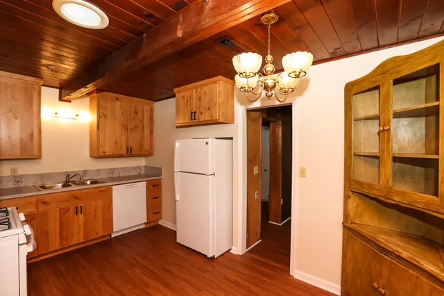 a kitchen with stainless steel appliances granite countertop a refrigerator a sink dishwasher and a dining table with wooden floor