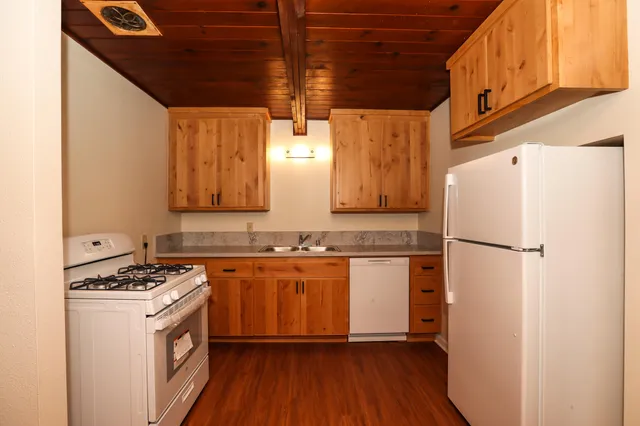 a kitchen with granite countertop a refrigerator a sink and wooden floor