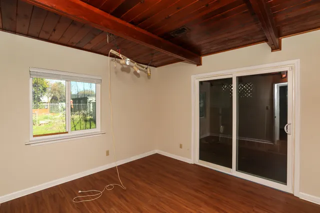 a view of an empty room with wooden floor and a window