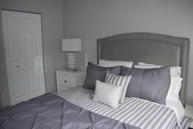 a bedroom with a bed and a lamp on dresser