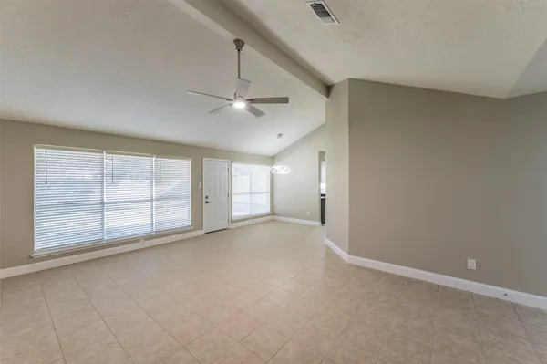 an empty room with chandelier fan and windows