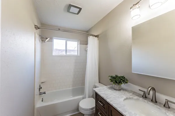 a bathroom with a granite countertop sink toilet a mirror and shower